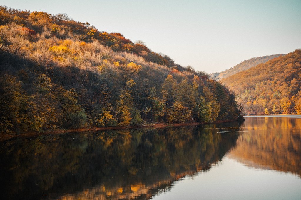 Wooded hillsides in autumn colour reflected in a calm lake